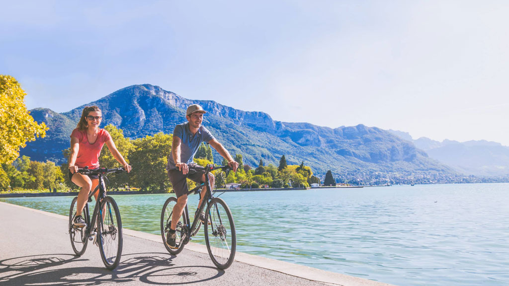 Couple de cyclistes faisant une pause face au château de Duingt sur le lac d'Annecy